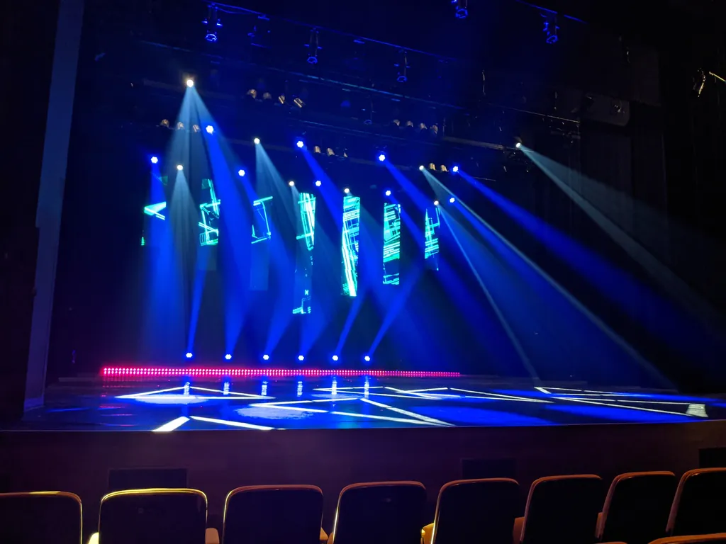 Scène de salle en éclairage bleu, faisceaux de projecteurs et écrans multimédia — spectacle d’école de danse hip-hop, multimédia et éclairage, Saint-Jean-sur-Richelieu.
